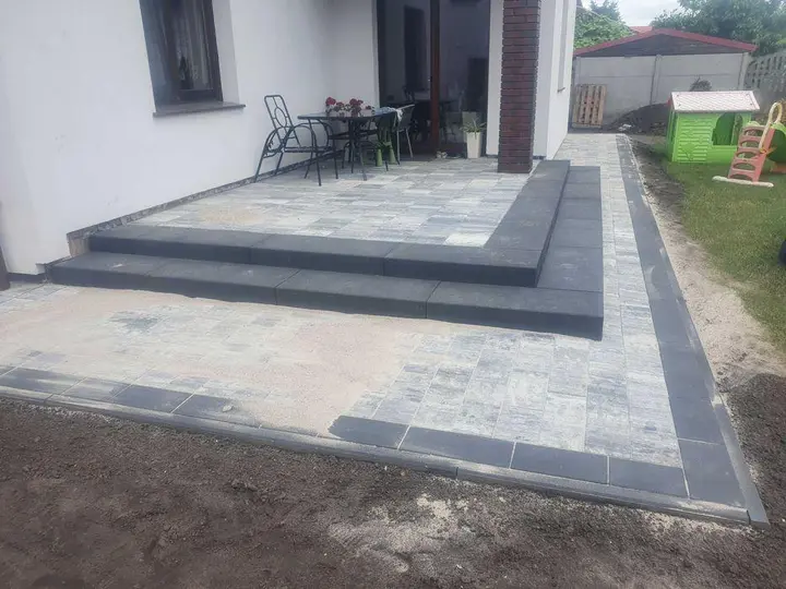 Taras z kostki brukowej z szerokimi grafitowymi stopniami blokowymi